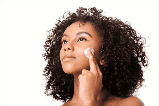 Woman applying moisturizer after steaming face at home
