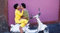 Young couple kissing on the back of a scooter