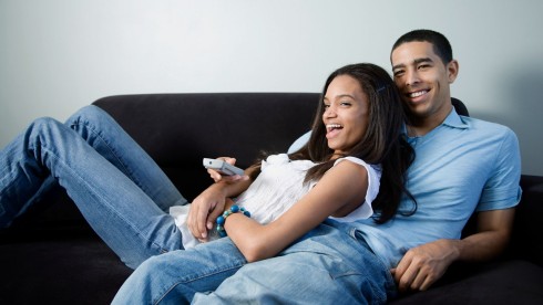 african american couple on couch watching tv