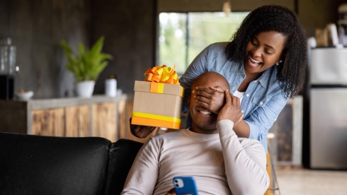 Woman at home surprising her husband with a gift