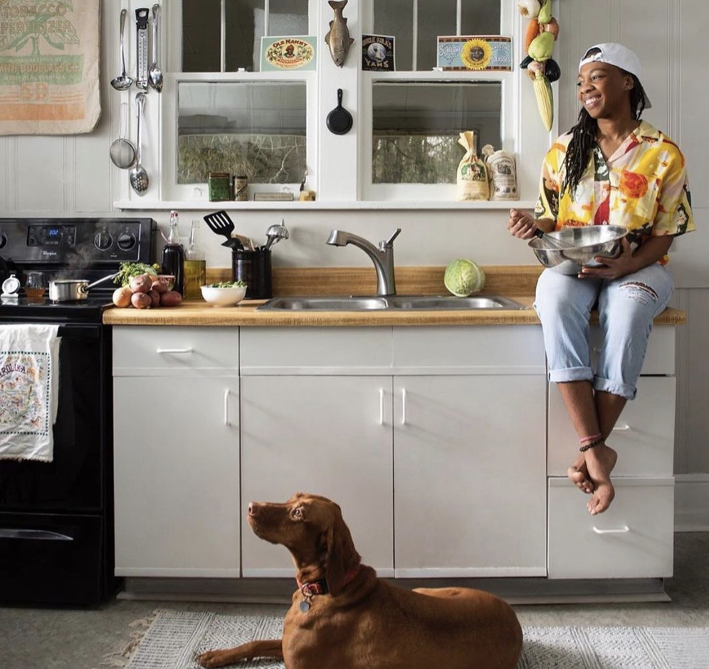 Ashleigh Shanti, a Black female chef sitting on a counter with a mixing bowl