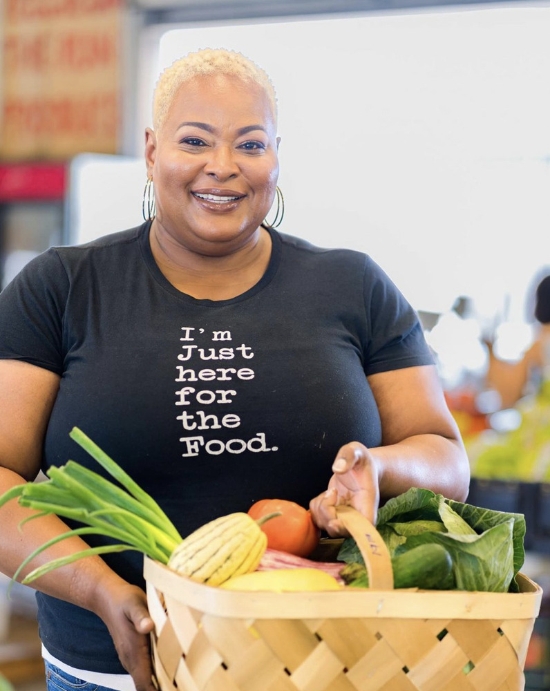 Black female chef Lisa Brooks posing with a basket of vegetables