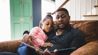 Black father reading to daughter_GettyImages