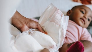 Mother swaddling child with Black-owned diaper