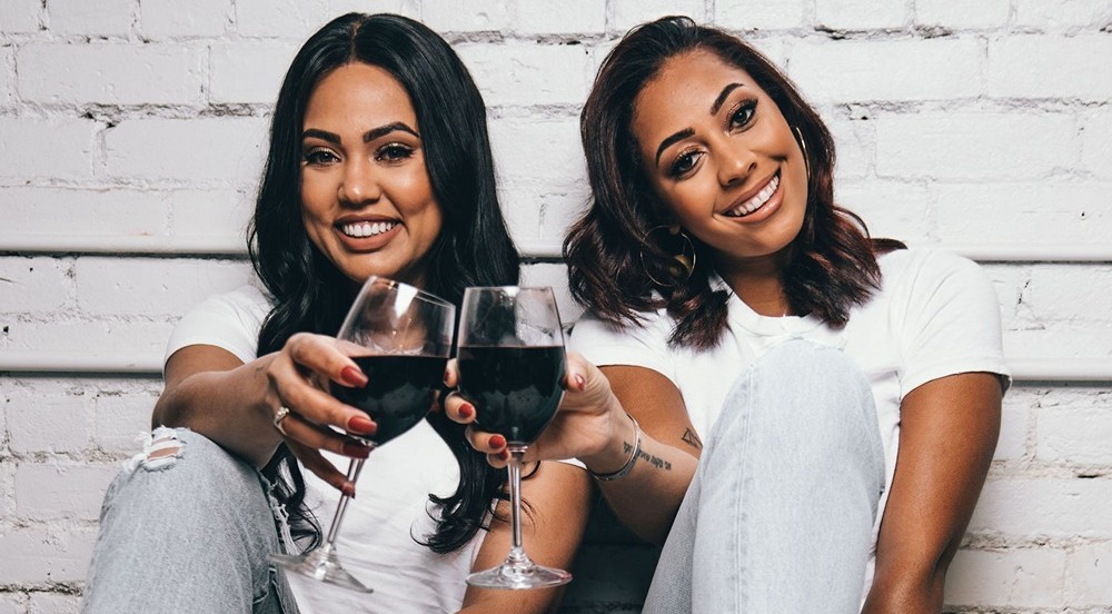 Ayesha Curry and Sydel Curry-Lee holding glasses of Domaine Curry Wine